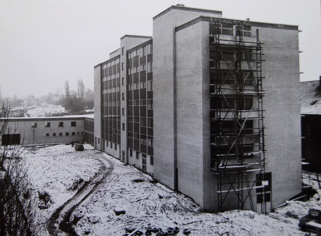 Schwarzweißaufnahme von Haus Gracht während der Bauphase mit Gerüst und Schnee auf der Baustelle.