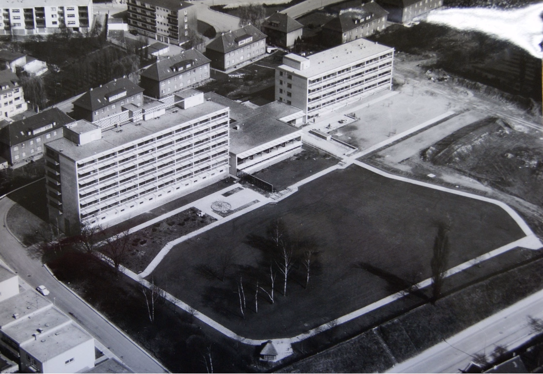Schwarzweiß-Luftaufnahme von Haus Gracht am Ende der Bauphase mit Gebäuden, Wegen und Grünflächen.